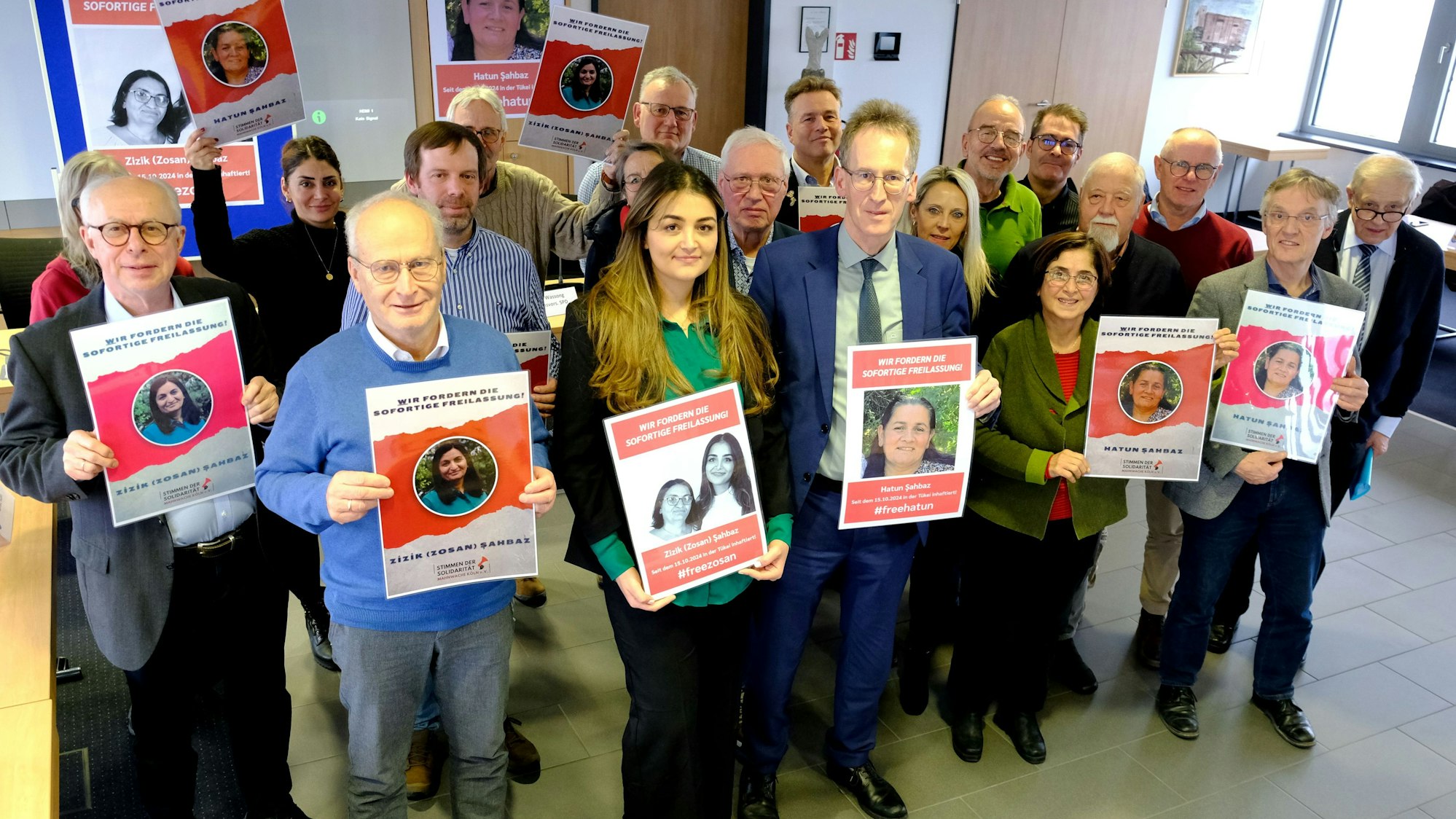 Archivbild vom 16.1.2025: Bürgermeister Dr. Hans-Peter Schick (vorne, 2.v.l.), Pinar Sahbaz und CDU-MdB Detlef Seif sowie Vertreter der Fraktionen von CDU, SPD, FDP, UWV und Grünen im Mechernicher Stadtrat halten Plakate mit den Porträts der Schwestern Zizik und Hatun Sahbaz aus Mechernich, die in der Türkei inhaftiert wurden.