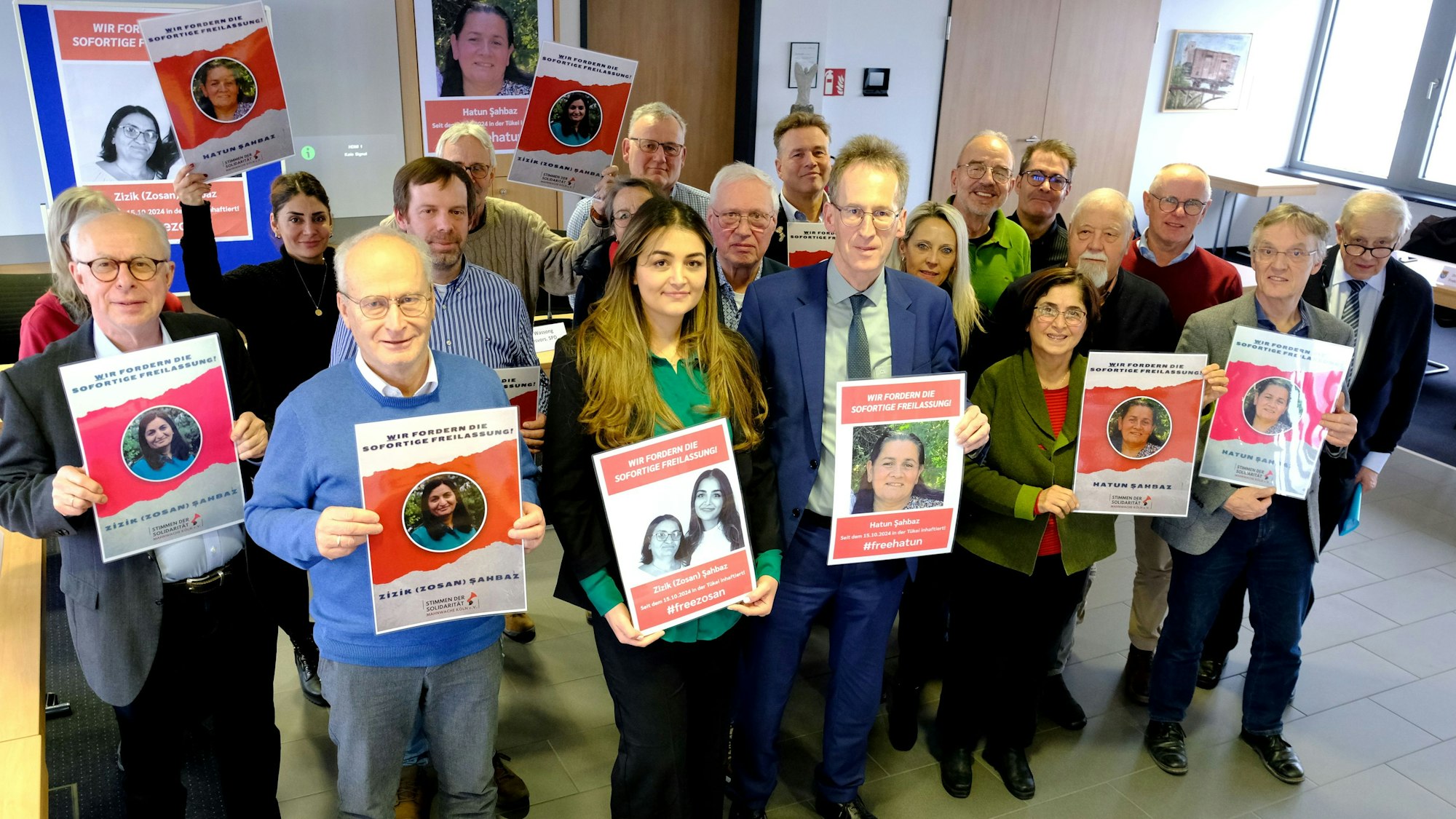 Bürgermeister Dr. Hans-Peter Schick (vorne, 2.v.l.), Pinar Sahbaz und CDU-MdB Detlef Seif sowie Vertreter der Fraktionen von CDU, SPD, FDP, UWV und Grünen im Mechernicher Stadtrat halten Plakate mit den Porträts der Schwestern Zizik und Hatun Sahbaz aus Mechernich, die in der Türkei inhaftiert wurden.