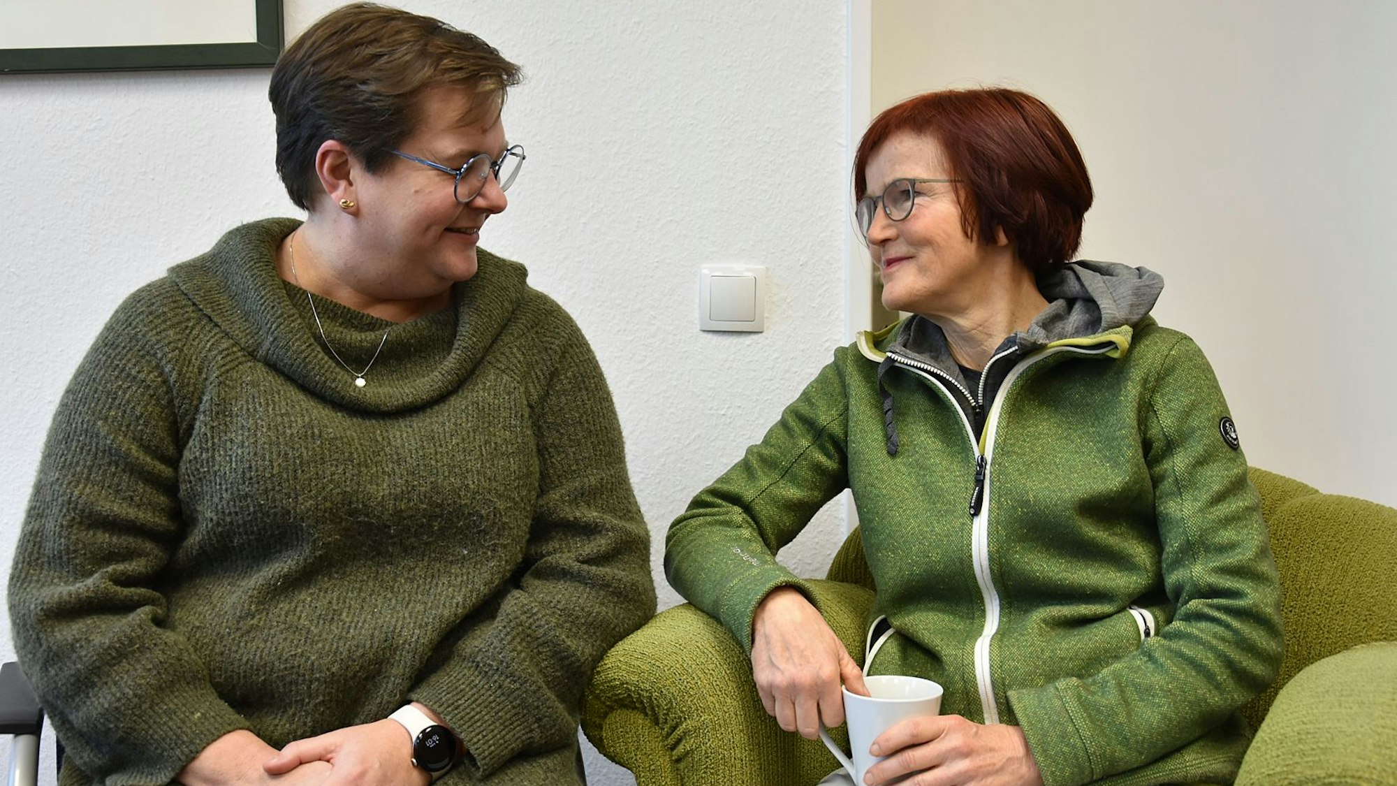 Zwei sitzende Frauen blicken sich freundlich an.