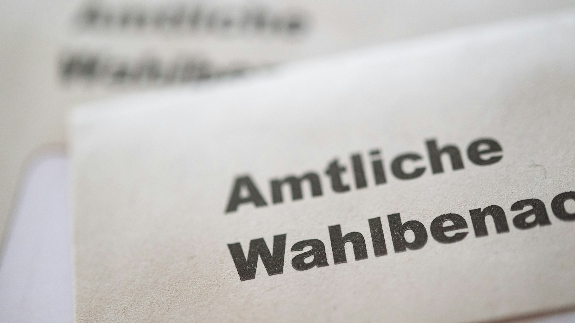 Eine amtliche Wahlbenachrichtigung zur Wahl zum Deutschen Bundestag am 23. Februar 2025 liegt auf einer zweiten Wahlbenachrichtigung.