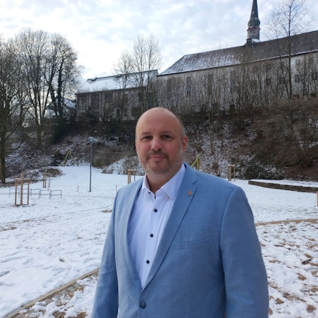 Porträt eines Mannes, der in einem schneebedeckten Park steht.