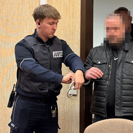 Ein Angeklagter wird in Handschellen in den Verhandlungssaal beim Kölner Landgericht geführt.