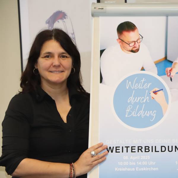 Eine Frau steht neben einem Plakat.