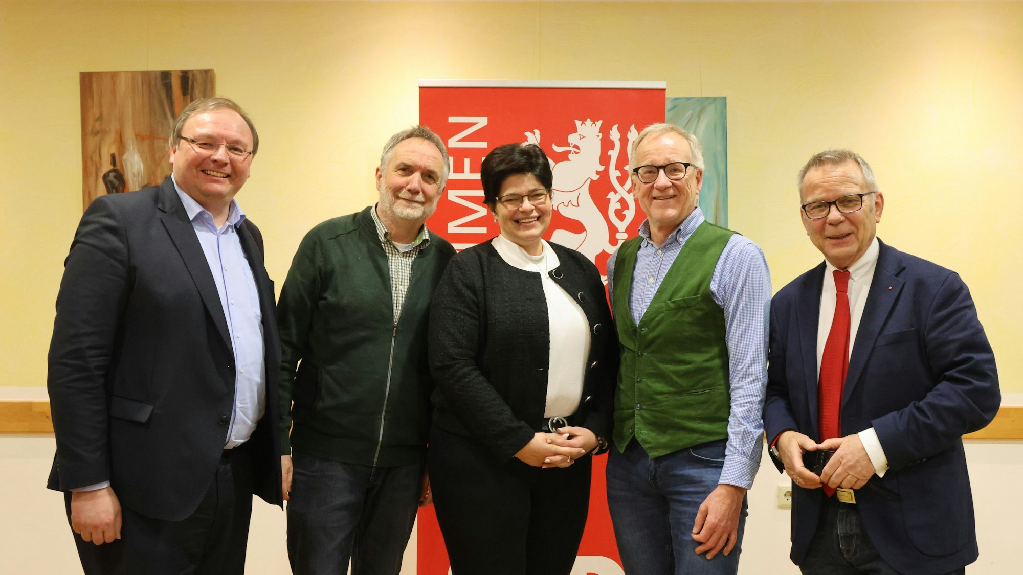 Vier Männer und eine Frau posieren vor einem SPD-Banner.