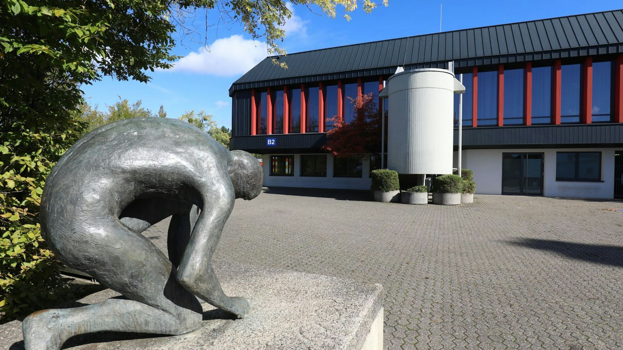 Eine Bronzestatue vor einem Trakt des Schulzentrums Oberpleis.