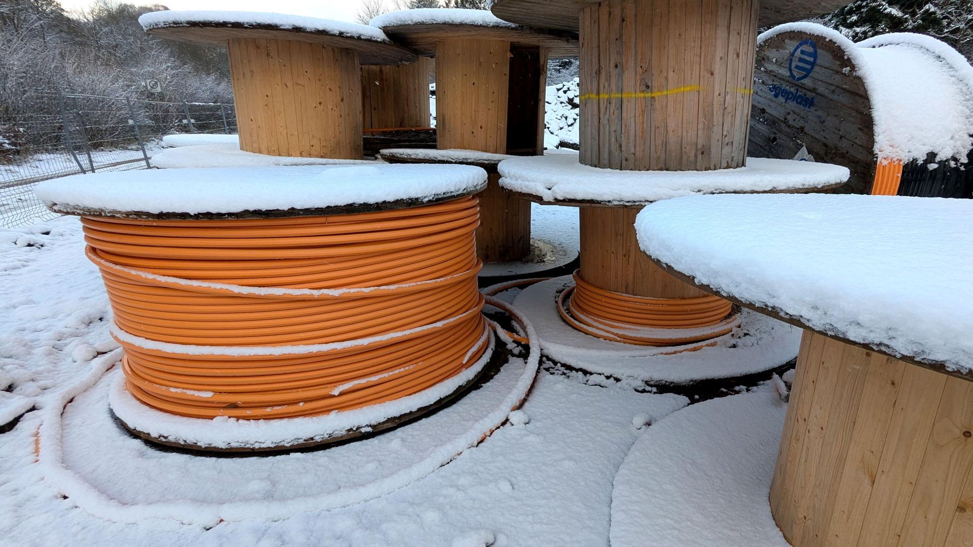 Kabeltrommeln mit Glasfaserleitungen im Schnee.