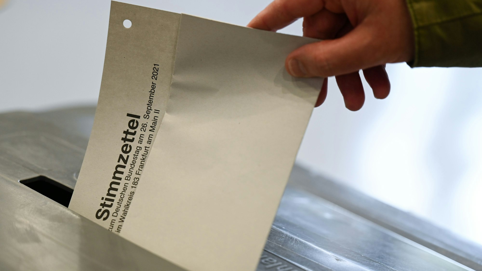 Ein Mann steckt im Wahllokal in der Freiherr-von-Stein-Schule im Stadtteil Sachsenhausen seinen Stimmzettel für die Bundestagswahl 2021 in eine Wahlurne.