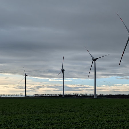 Windkraftanlagen sind vor einem bewölkten Himmel in Hürth zu sehen.