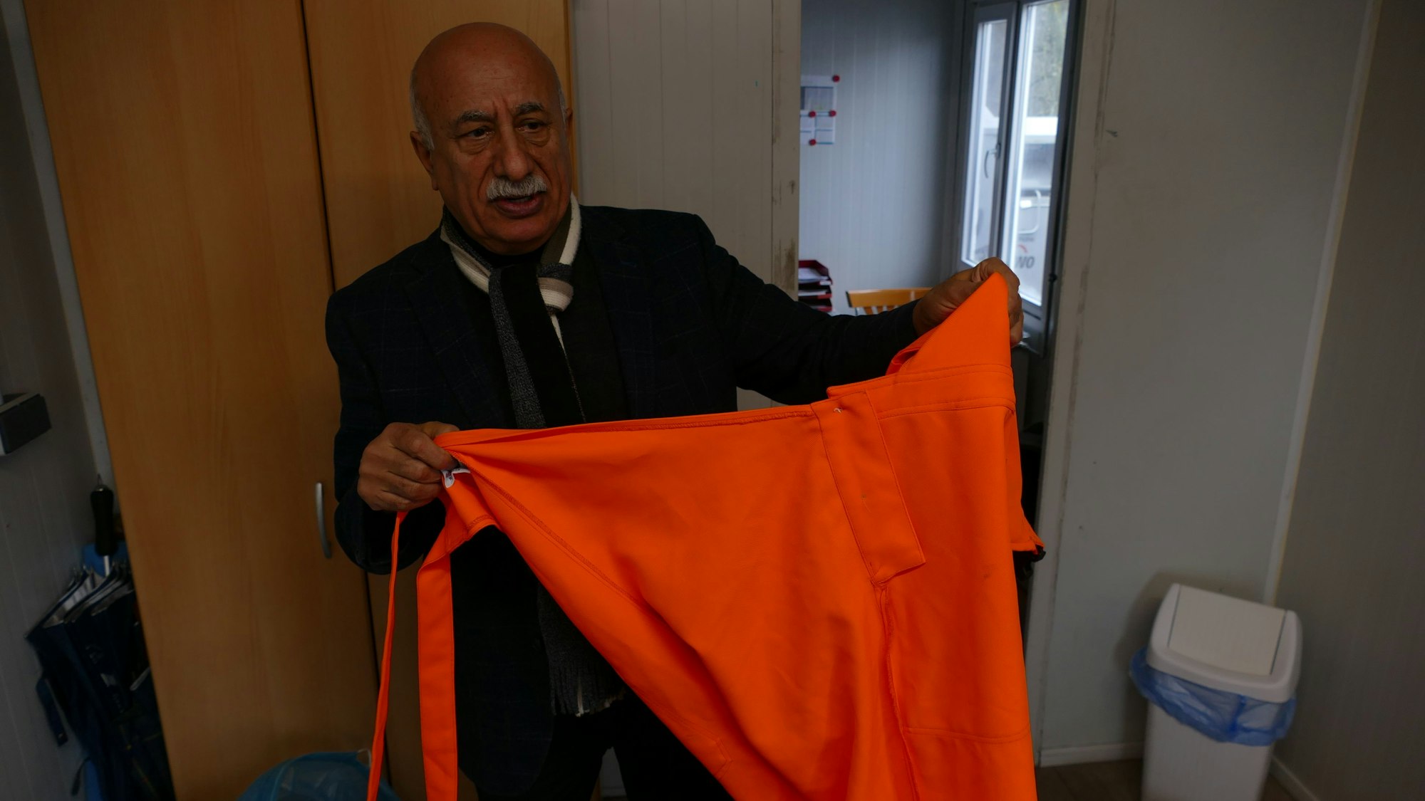 Ein Mann hält ein rotes T-Shirt in die Höhe.