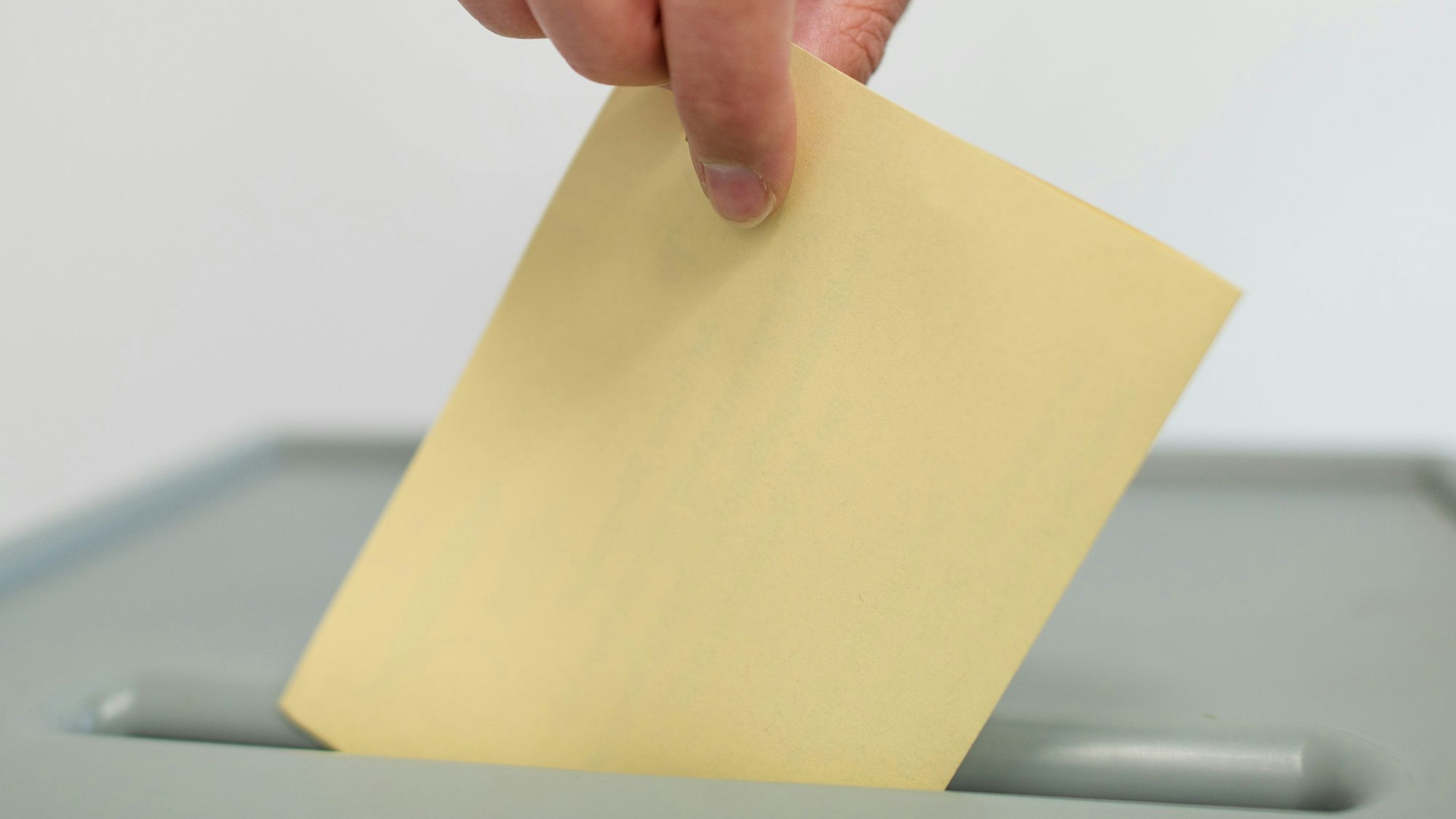 Ein Stimmzettel wird in eine Wahlurne geworfen.
