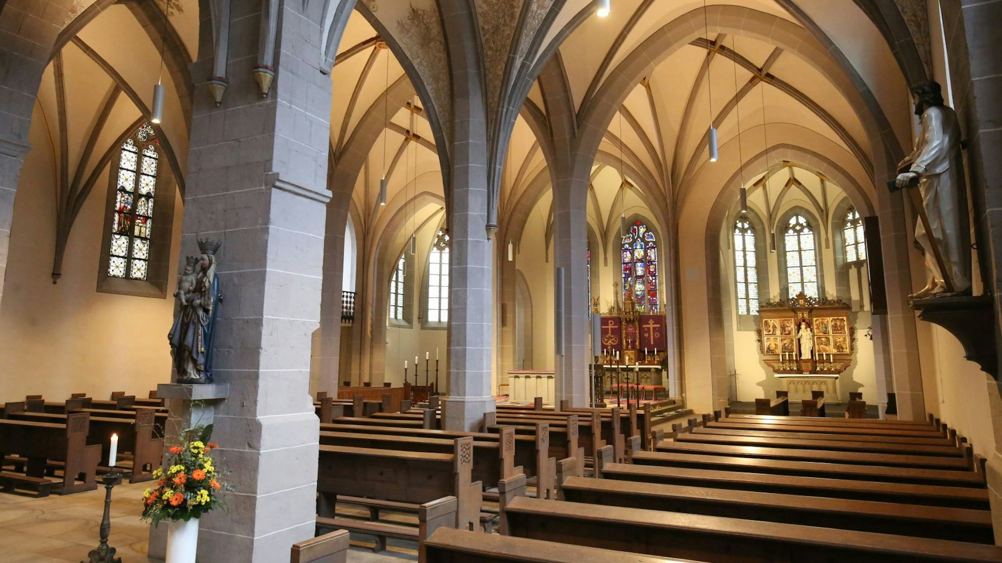 Blick in das Innere einer Kirche, im Vordergrund die Kirchenbänke, im Hintergrund zwei Altäre.