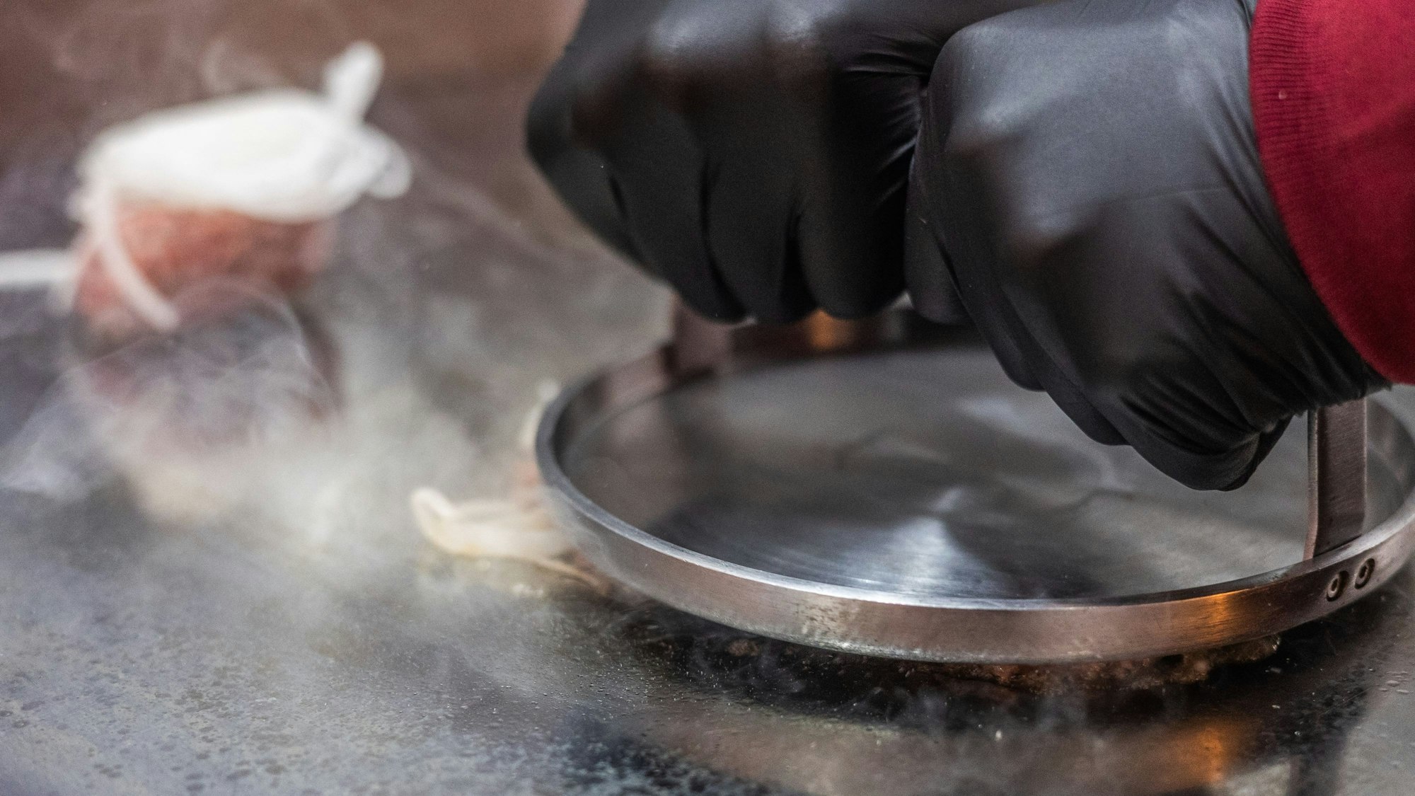Auf der Grillplatte wird das Fleisch platt gedrückt.