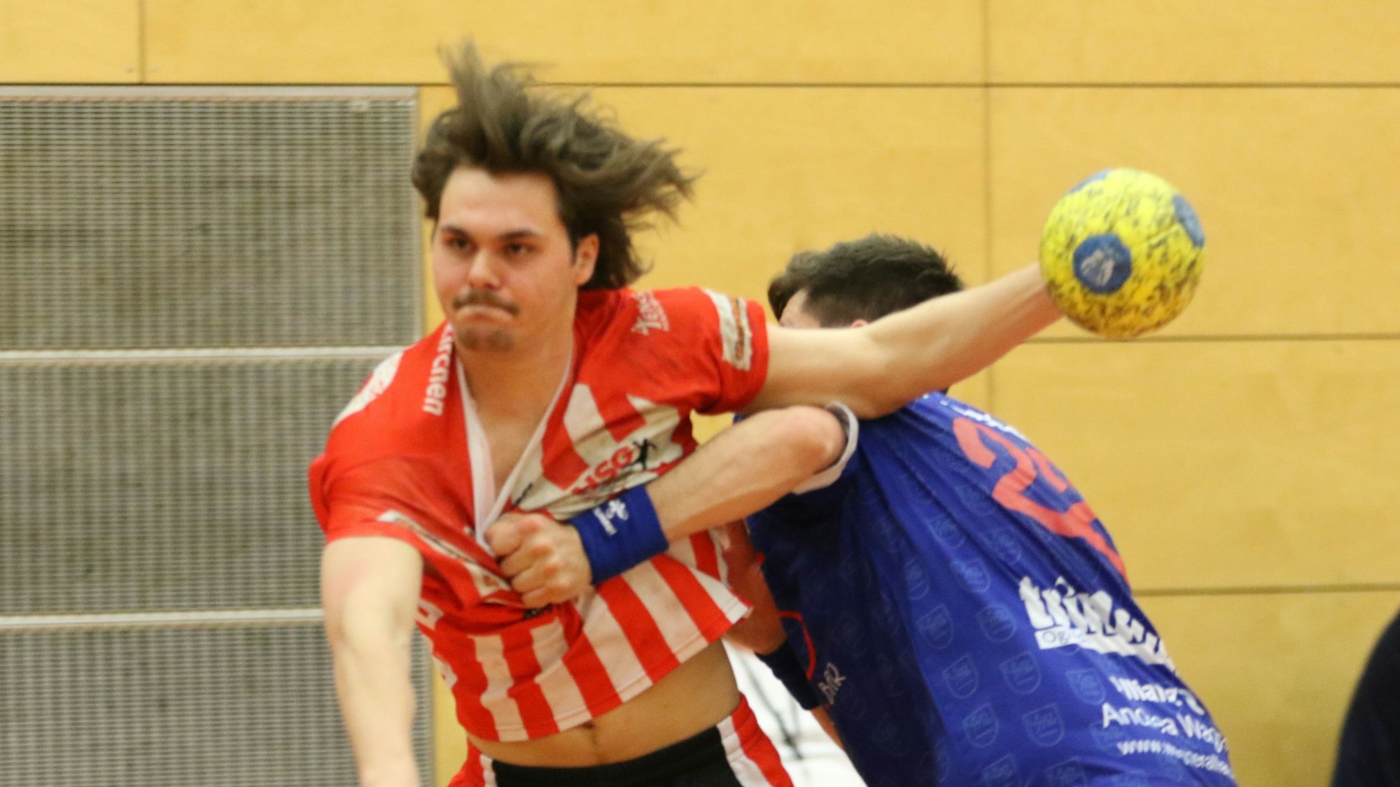 Euskirchens Jarl Schramm hat den Ball wurfbereit in der Hand und wird von einem Gegner am Trikot gezerrt.