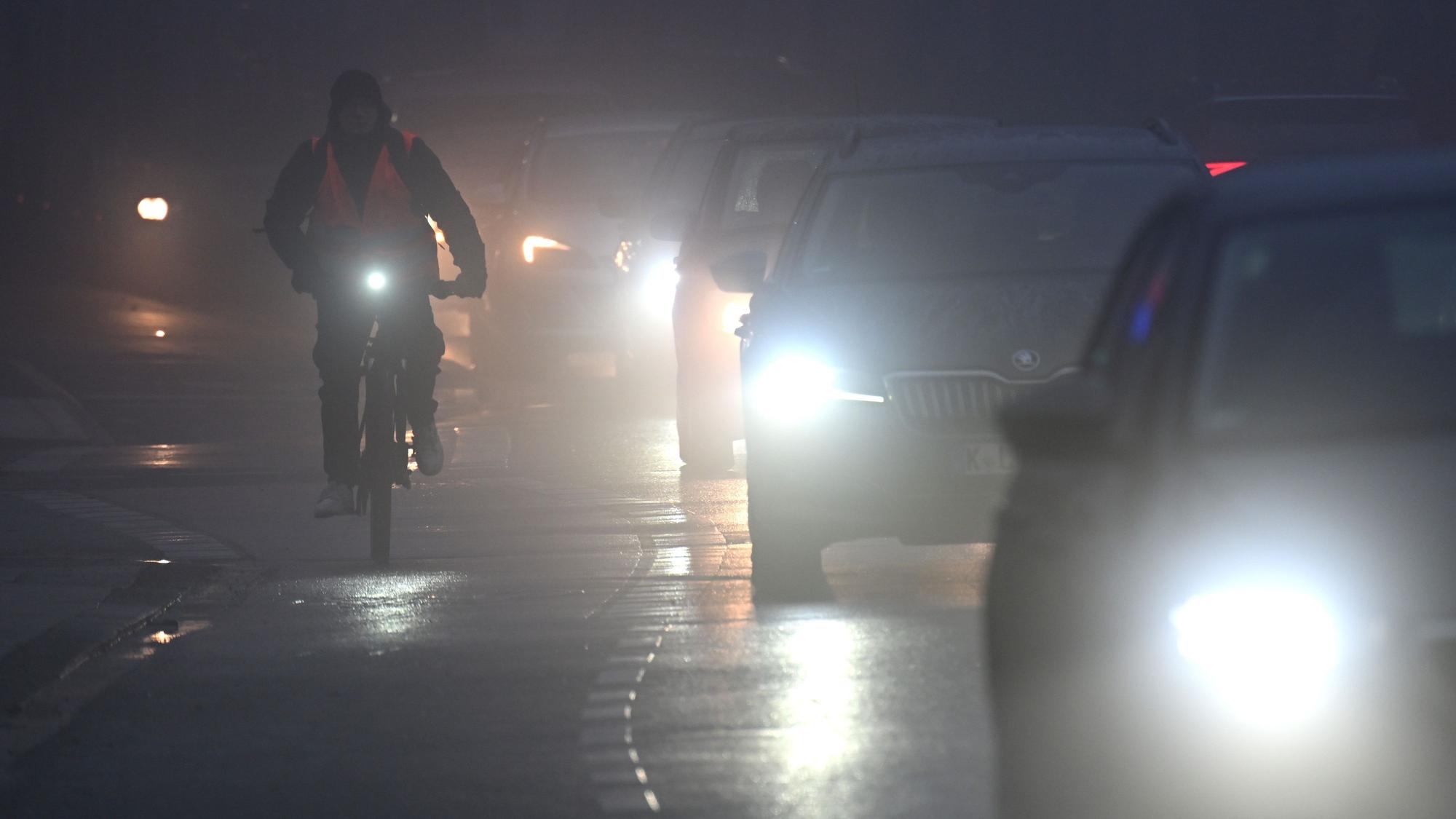 15.01.2025, Nordrhein-Westfalen, Köln: Fahrräder und Autos fahren am Morgen durch den Nebel.