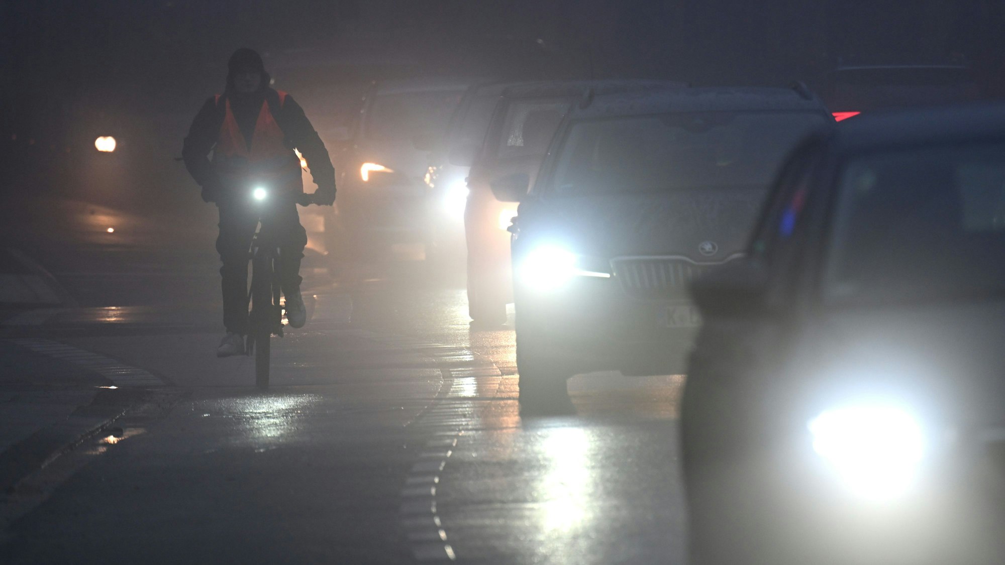 15.01.2025, Nordrhein-Westfalen, Köln: Fahrräder und Autos fahren am Morgen durch den Nebel.