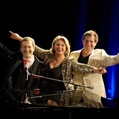 Alex Parker (v.l.), Gabriela Benesch und Erich Furrer stehen nebeneinander und recken die Arme zur Seite.