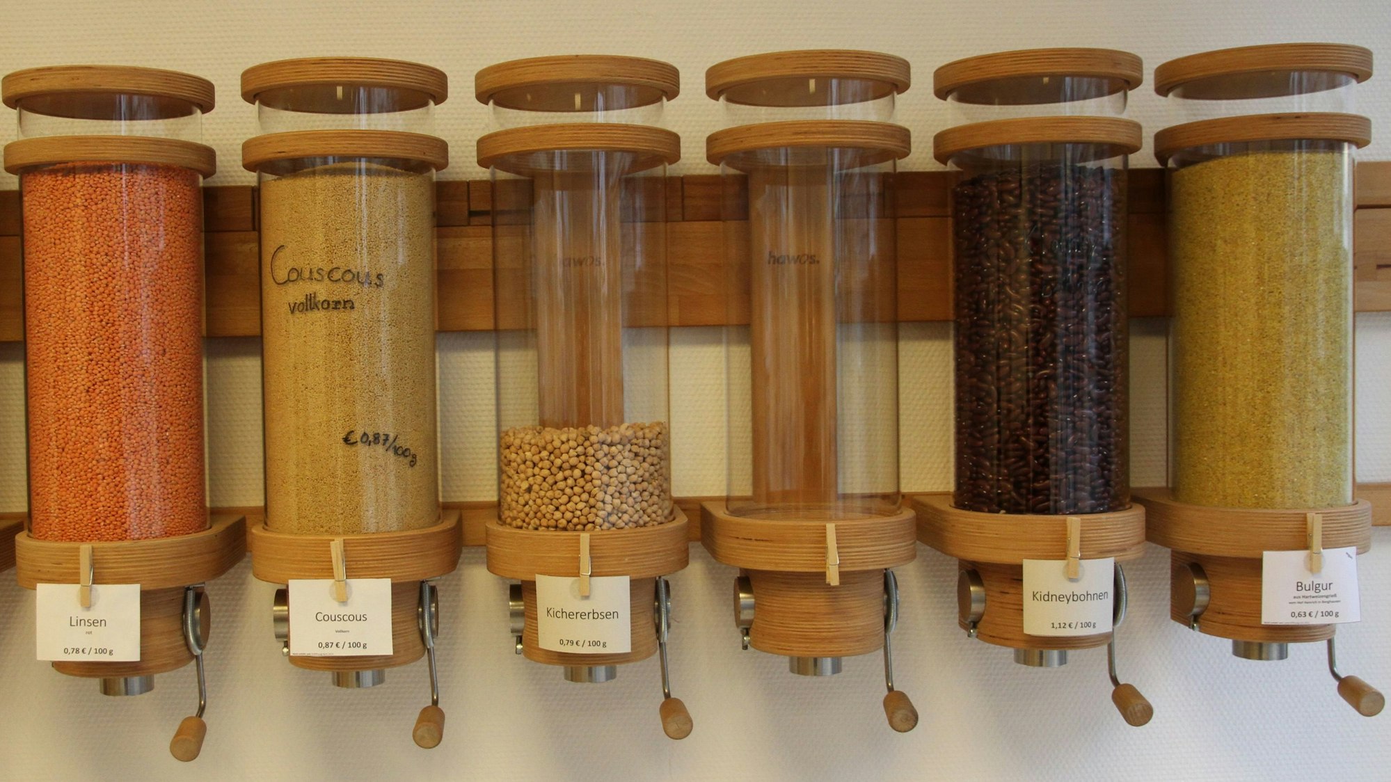 Sechs Glasbehälter mit verschiedenen Hülsefrüchten und Getreidesorten.