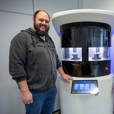 Zwei junge Männer stehen neben einer Maschine.