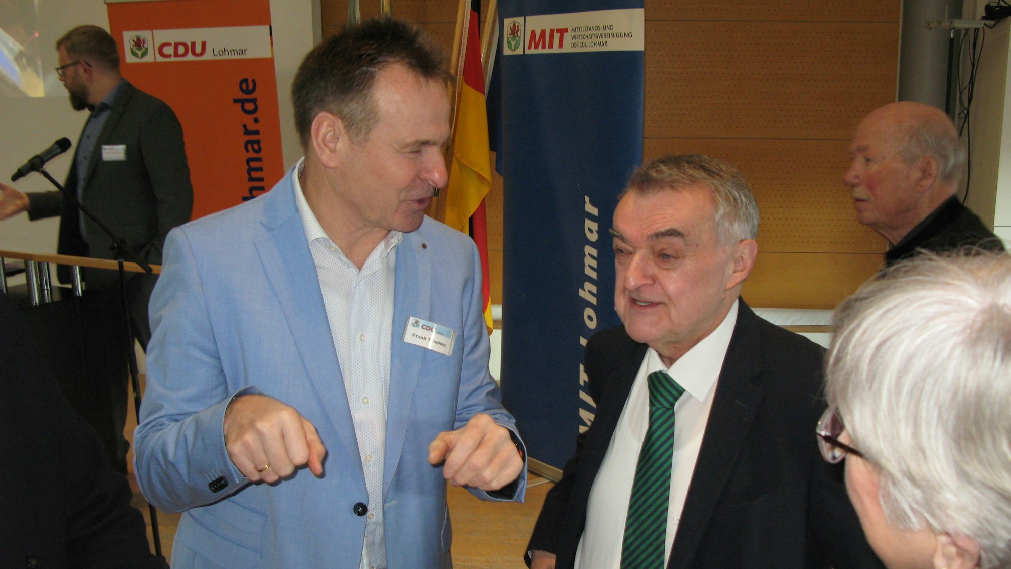 Zwei Männer und eine Frau unterhalten sich an einem Stehtisch.