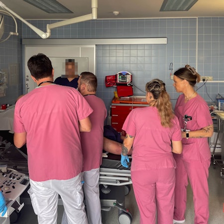 Mitarbeiter der Zentralen Notaufnahme des Marien-Hospitals in Euskirchen in rosafarbener Arbeitskleidung kümmern sich um einen Patienten.