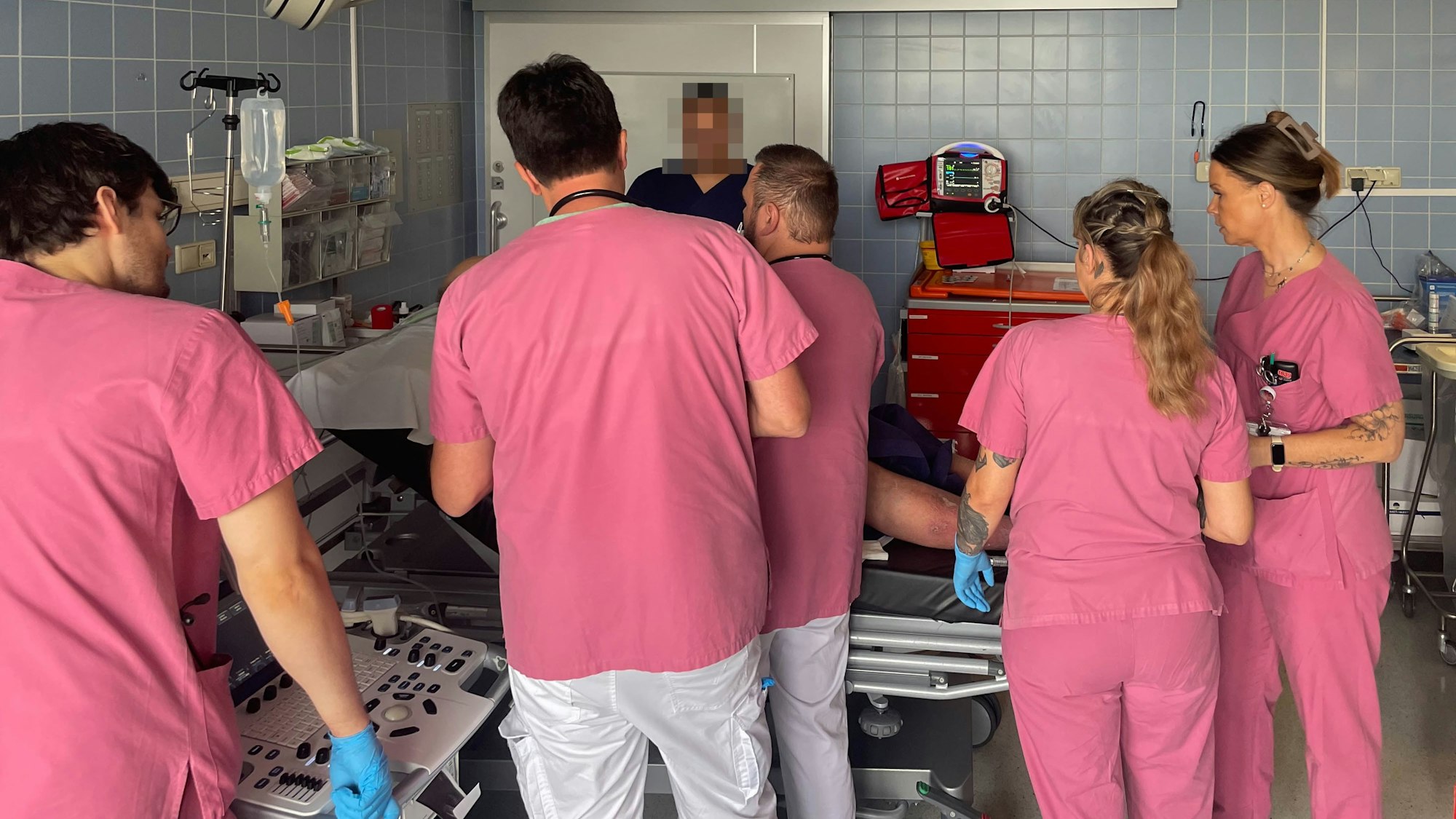 Mitarbeiter der Zentralen Notaufnahme des Marien-Hospitals in Euskirchen in rosafarbener Arbeitskleidung kümmern sich um einen Patienten.