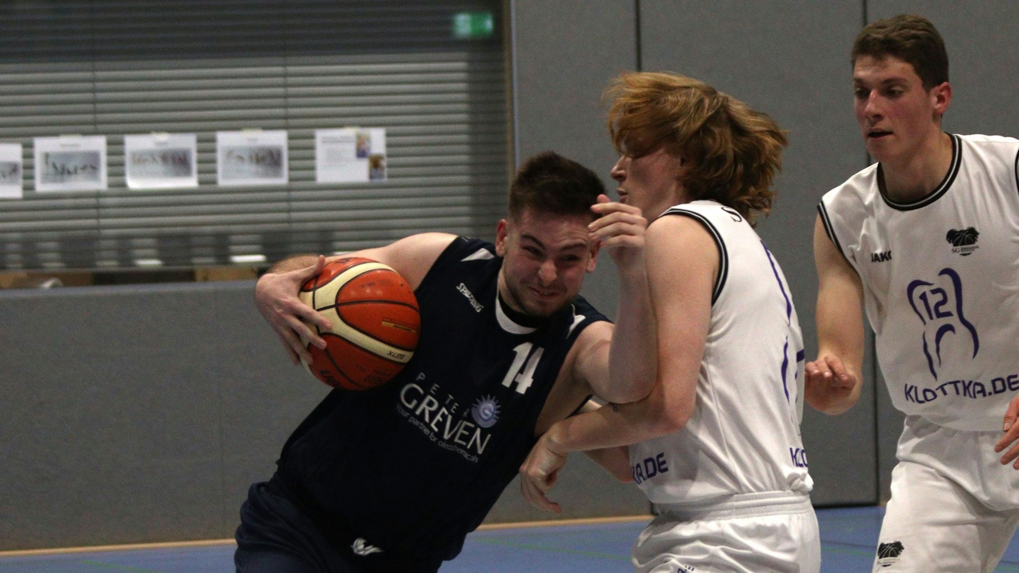 Erftbaskets-Spieler Chris Beier hält den Ball mit einem Arm an den Körper gepresst und schiebt sich mit dem anderen in den Gegenspieler hinein.
