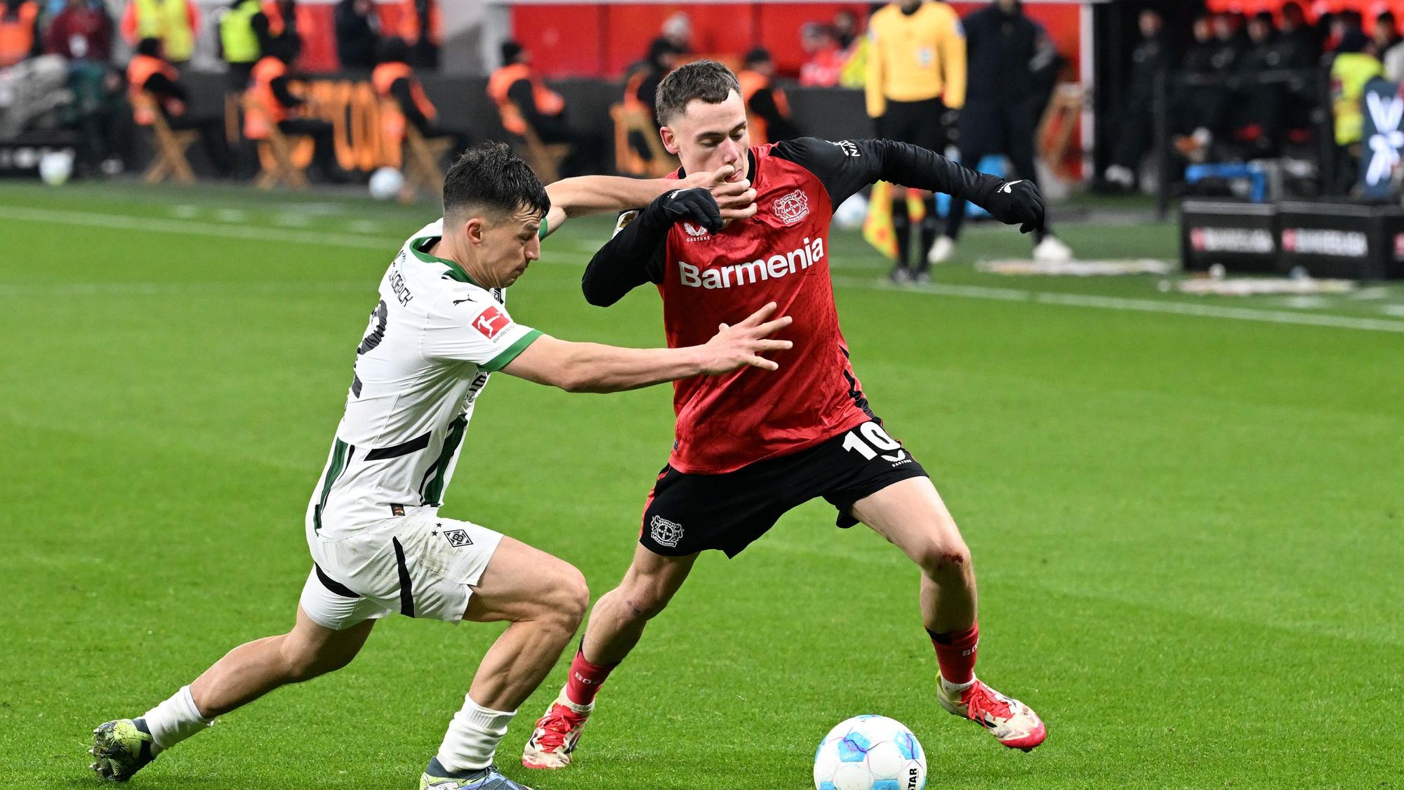 Leverkusens Florian Wirtz (r) und Gladbachs Stefan Lainer kämpfen um den Ball.