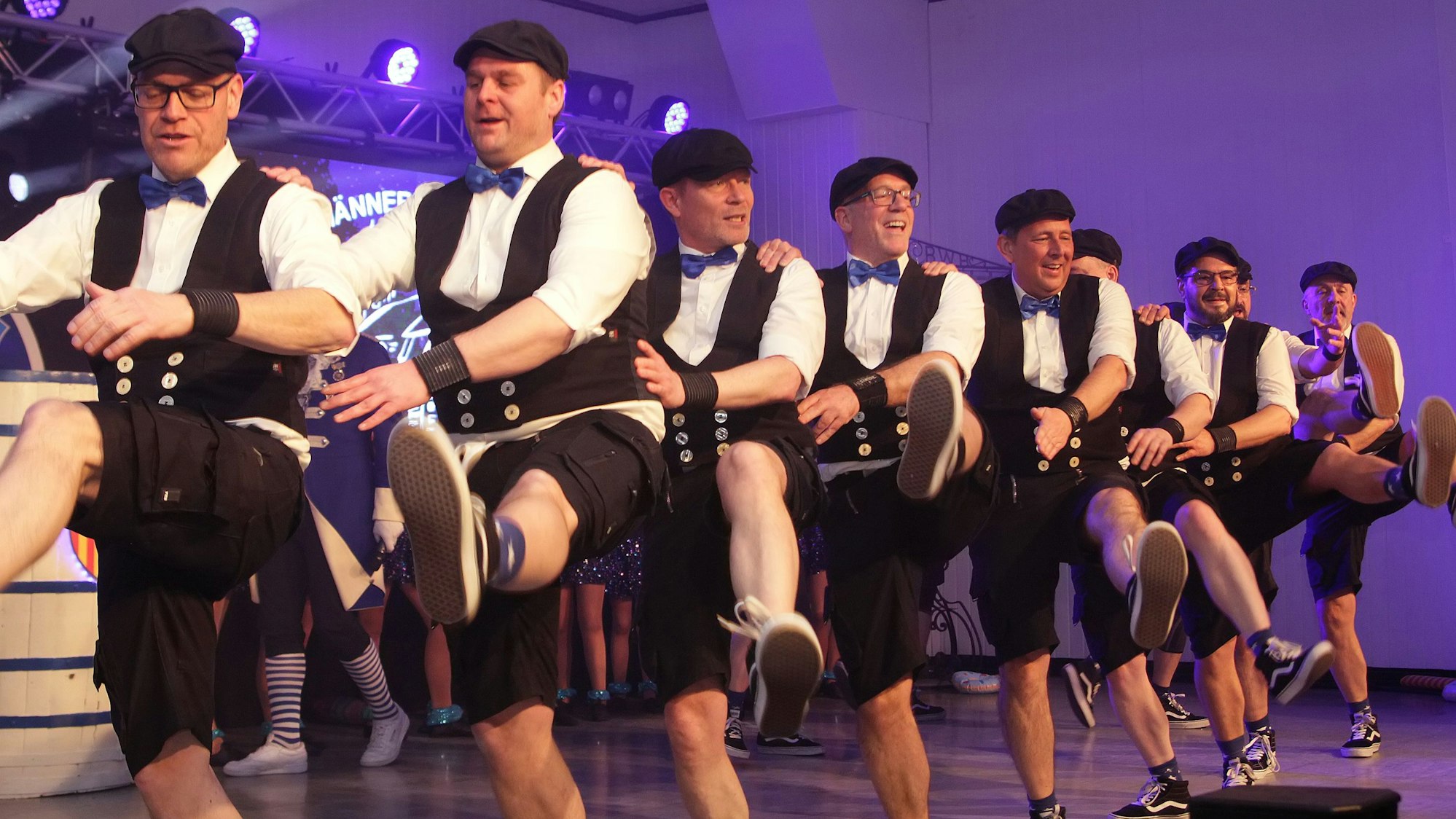 Zu sehen sind tanzende Männer in kurzen Hosen.