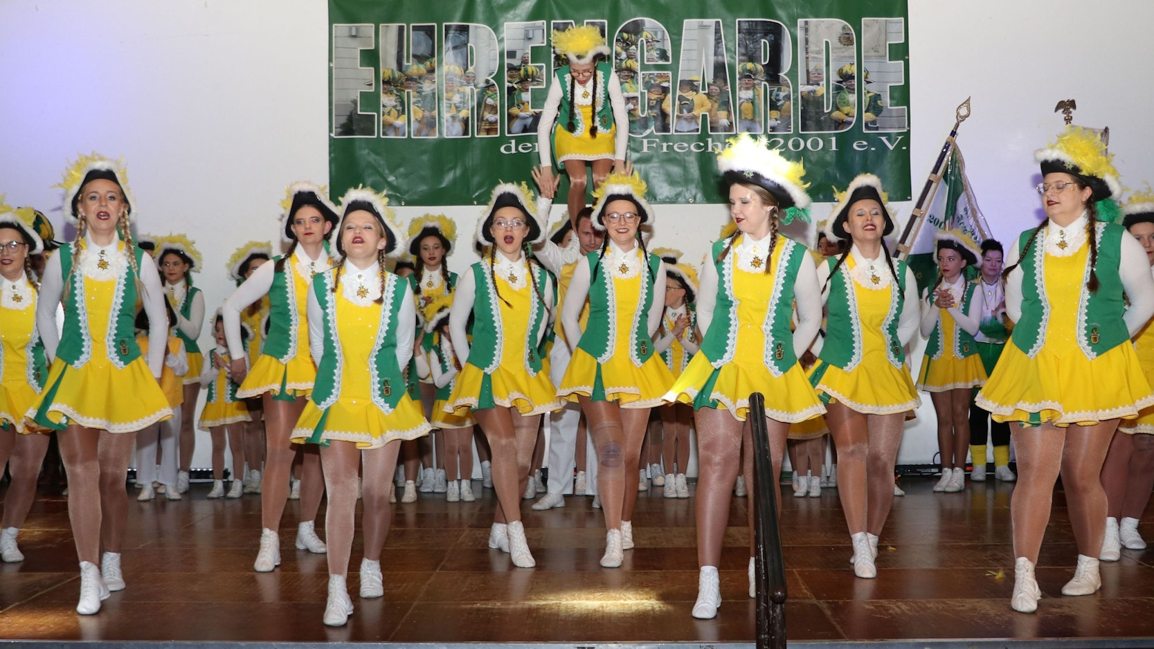 Zu sehen sind Tänzerinnen einer Karnevalsgesellschaft in grün-gelben Gardeuniformen.