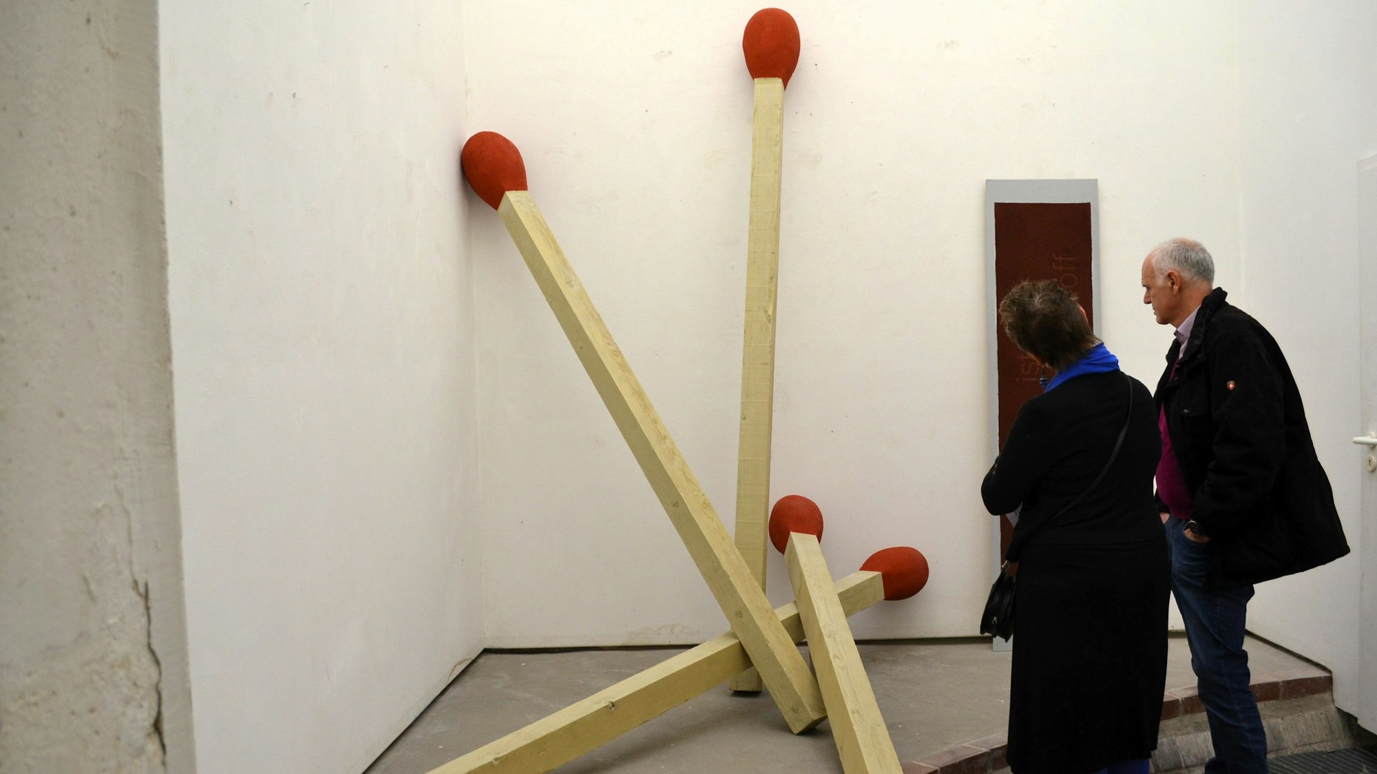 Übergroße Streichölzer lehnen an der Wand.