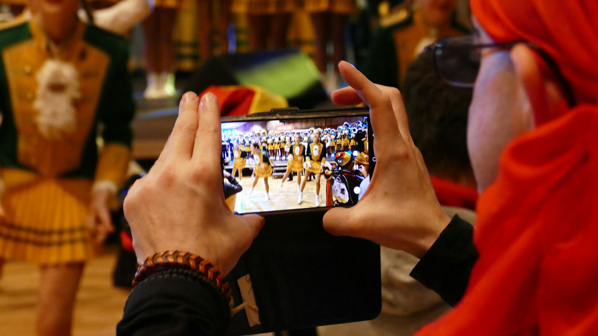 Eine Person filmt den Auftritt einer Tanzgruppe mit dem Smartphone.