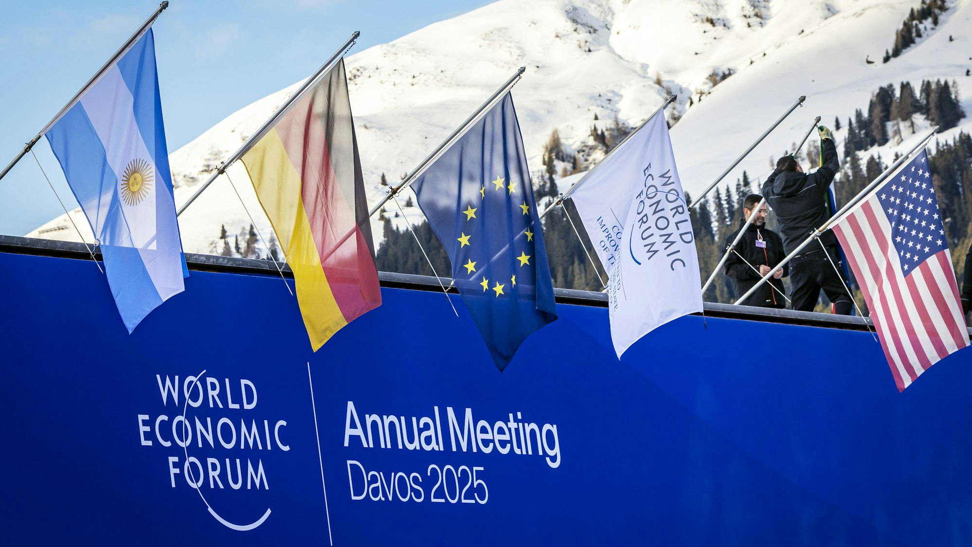 20.01.2025, Schweiz, Davos: Mitarbeiter hängen Fahnen am Kongresszentrum auf, kurz vor dem beginn des 55. Jahrestreffens des Weltwirtschaftsforum (WEF) in Davos, Schweiz. Foto: Michael Buholzer/KEYSTONE/dpa +++ dpa-Bildfunk +++
