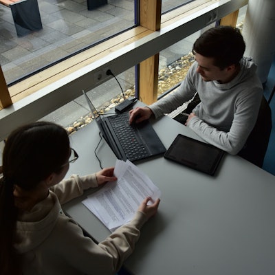 Junge Leute sitzen an einem Tisch und arbeiten am Laptop.