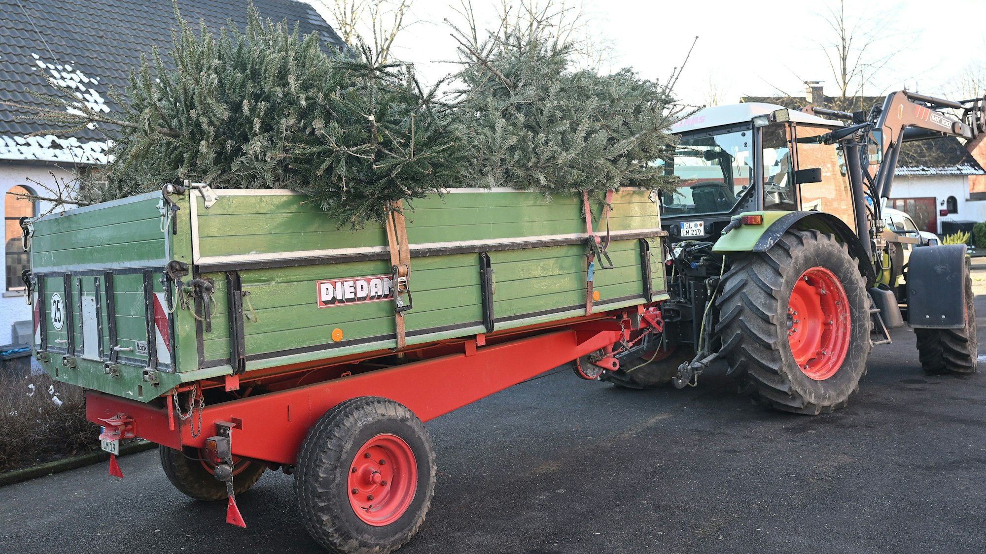 Ein Traktor fährt mit Bäumen vom Hof an der katholischen Kirche in Heiligenhaus.