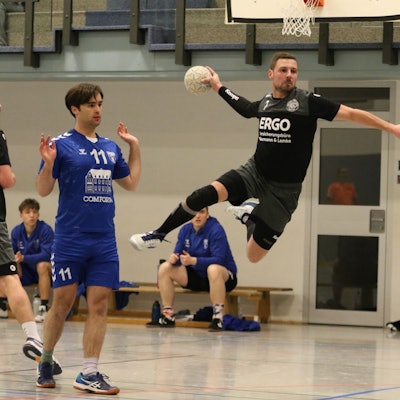 Kalls Handballer Christopher Schmitz steht beim Sprungwurf in der Luft. Sein Gegenspieler hebt die Hände und will mit der Sache nichts zu tun haben.