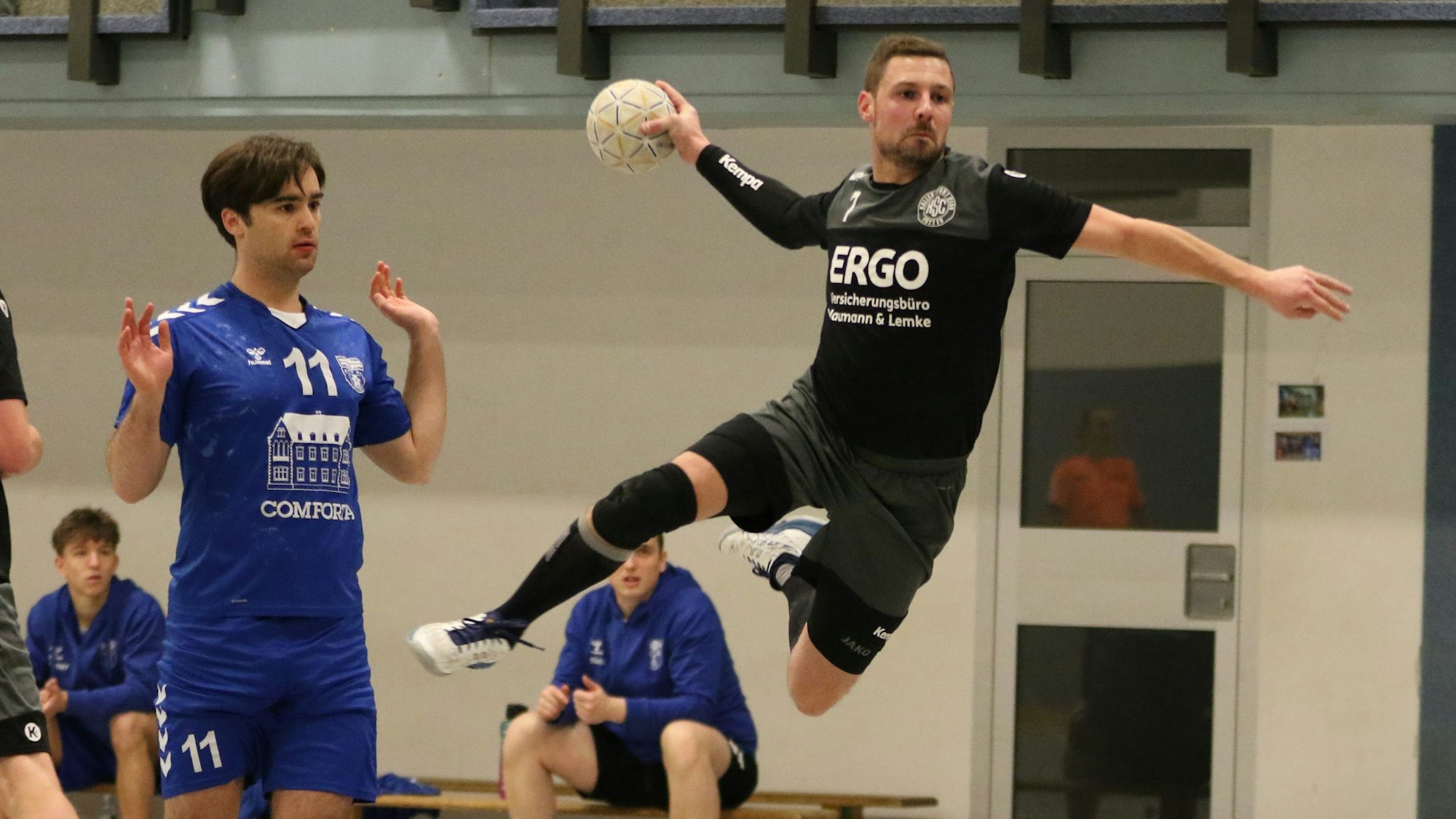 Kalls Handballer Christopher Schmitz steht beim Sprungwurf in der Luft. Sein Gegenspieler hebt die Hände und will mit der Sache nichts zu tun haben.