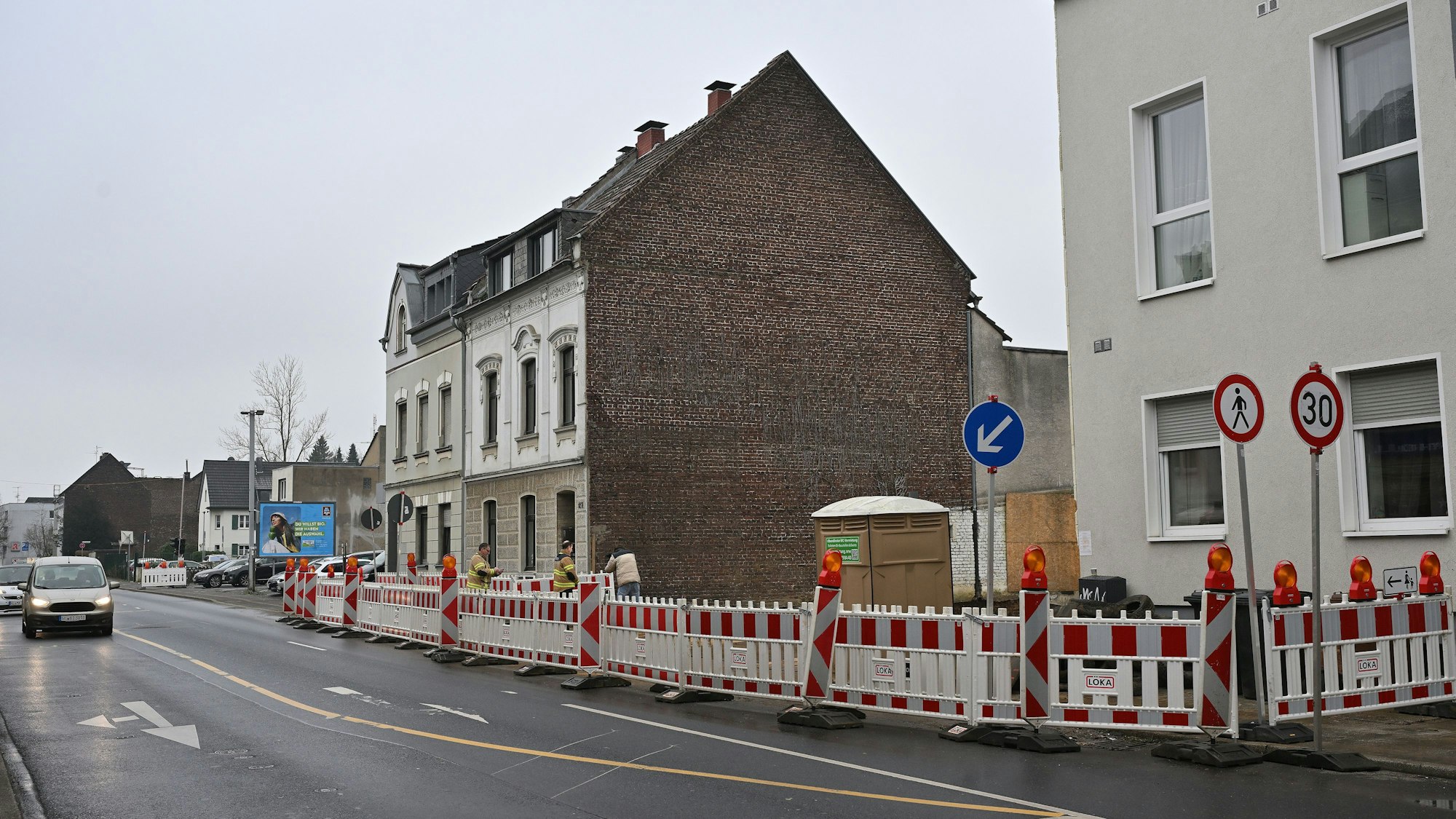 Absperrgitter sperren die Baugrube ab. Die Fahrbahn ist etwas verengt dadurch.