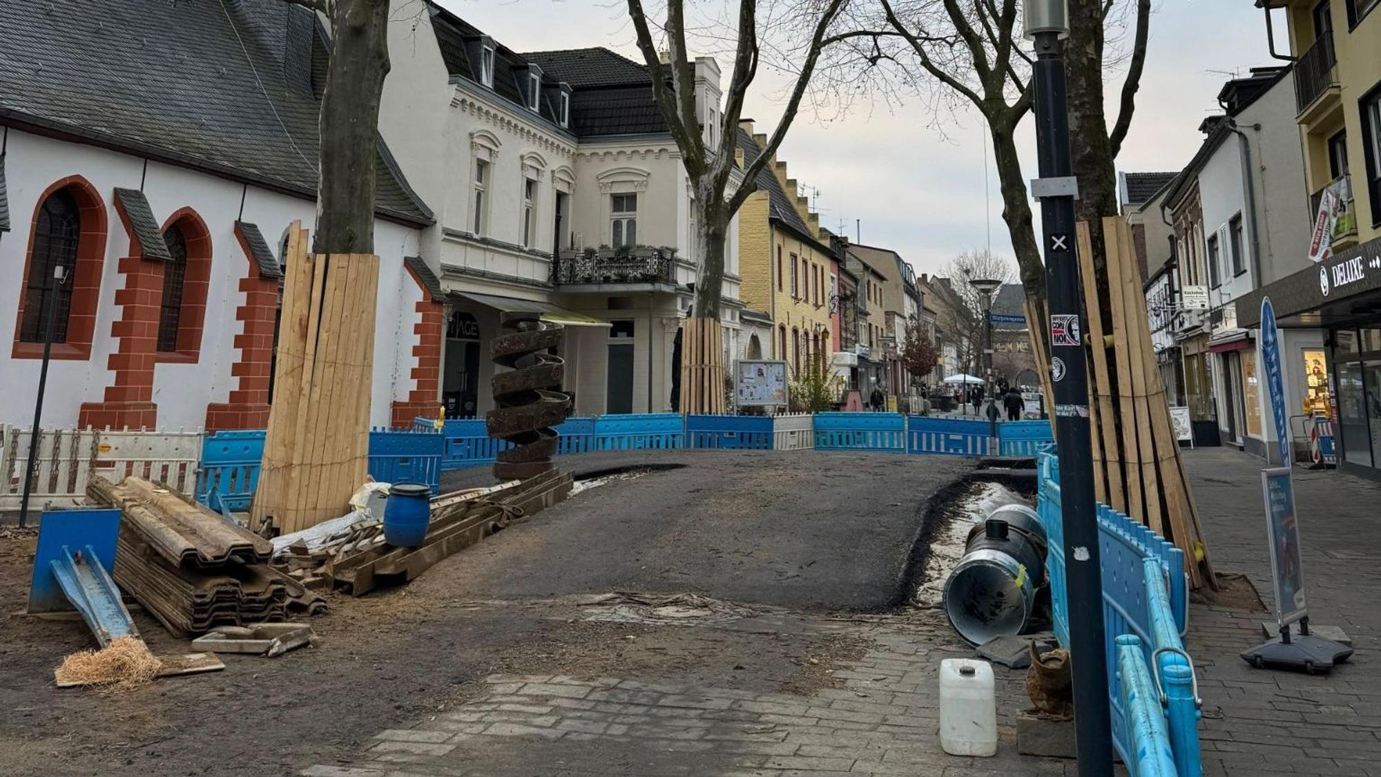 Das Foto zeigt eine Asphaltbrücke zwischen Bäumen in der Bergheimer Innenstadt.