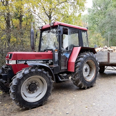 Ein älterer, roter Traktor steht im November 2023 mit einer Fuhre Holz auf einem Waldweg.