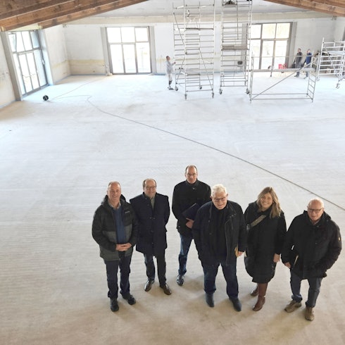 Hermann-Josef Esser, Stefan Kupp, Lothar Schatten, Gottfried Schnitzler, Nadine Schwendtner und Alois Poth vom Bürgerverein stehen in der leeren Halle, im Hintergrund sind Gerüstwagen zu sehen.