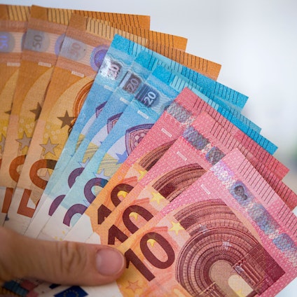 Eine Person hält Banknoten gefächert in der Hand.