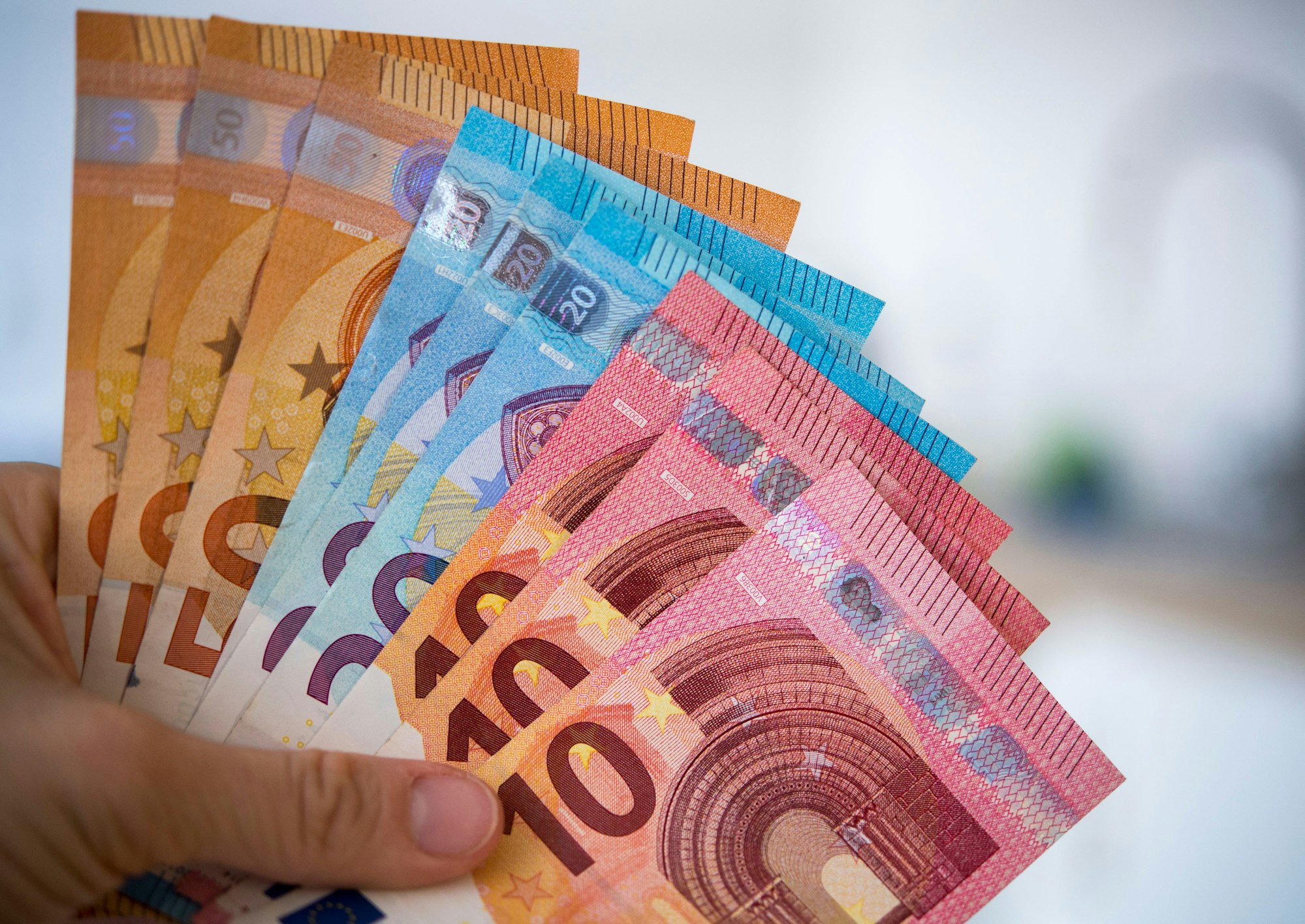 Eine Person hält Banknoten gefächert in der Hand.