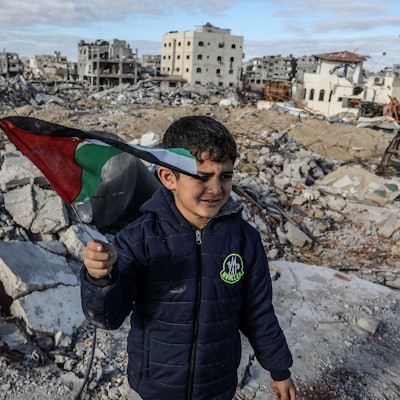 Ein vertriebener palästinensischer Junge, der eine Fahne schwenkt, steht auf Trümmern von Gebäuden, einen Tag nach Inkrafttreten eines Abkommens über eine Waffenruhe zwischen Israel und der Hamas im Gazastreifen.