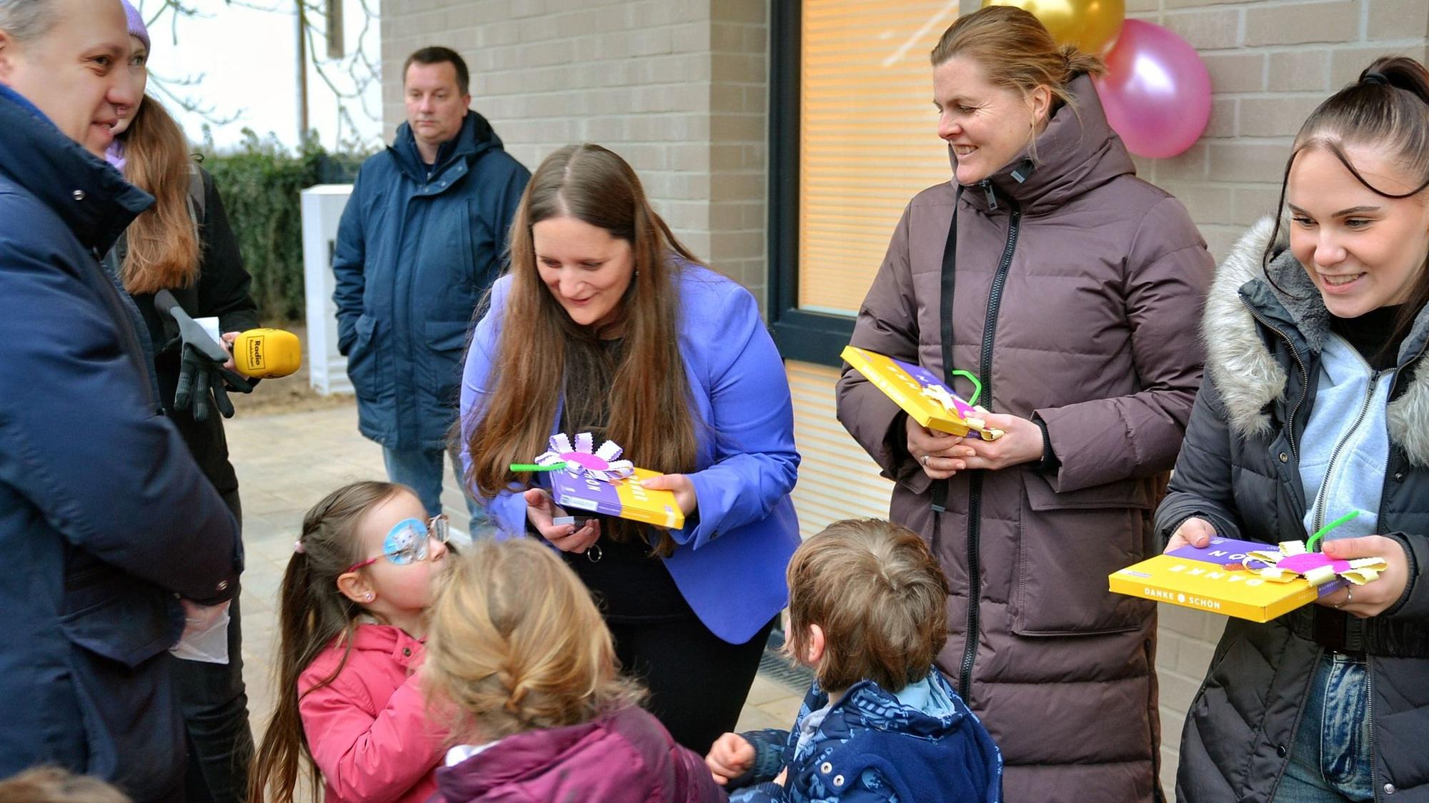 Die Erzieherinnen, umringt von Kindern und Erwachsenen, haben Schokoladenpackungen in der Hand.
