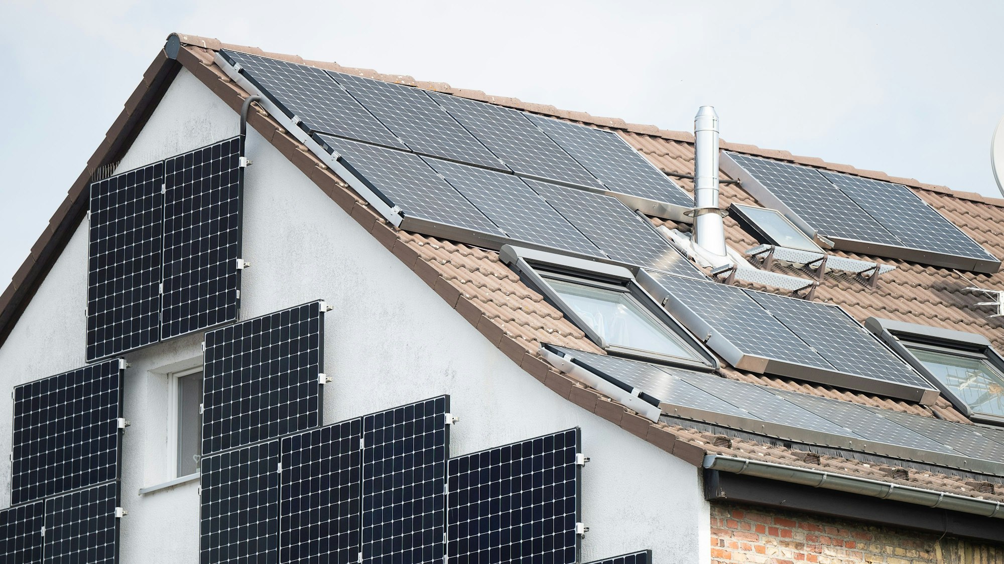 Solarpanel sind an der Fassade und auf dem Dach eines Hauses befestigt.