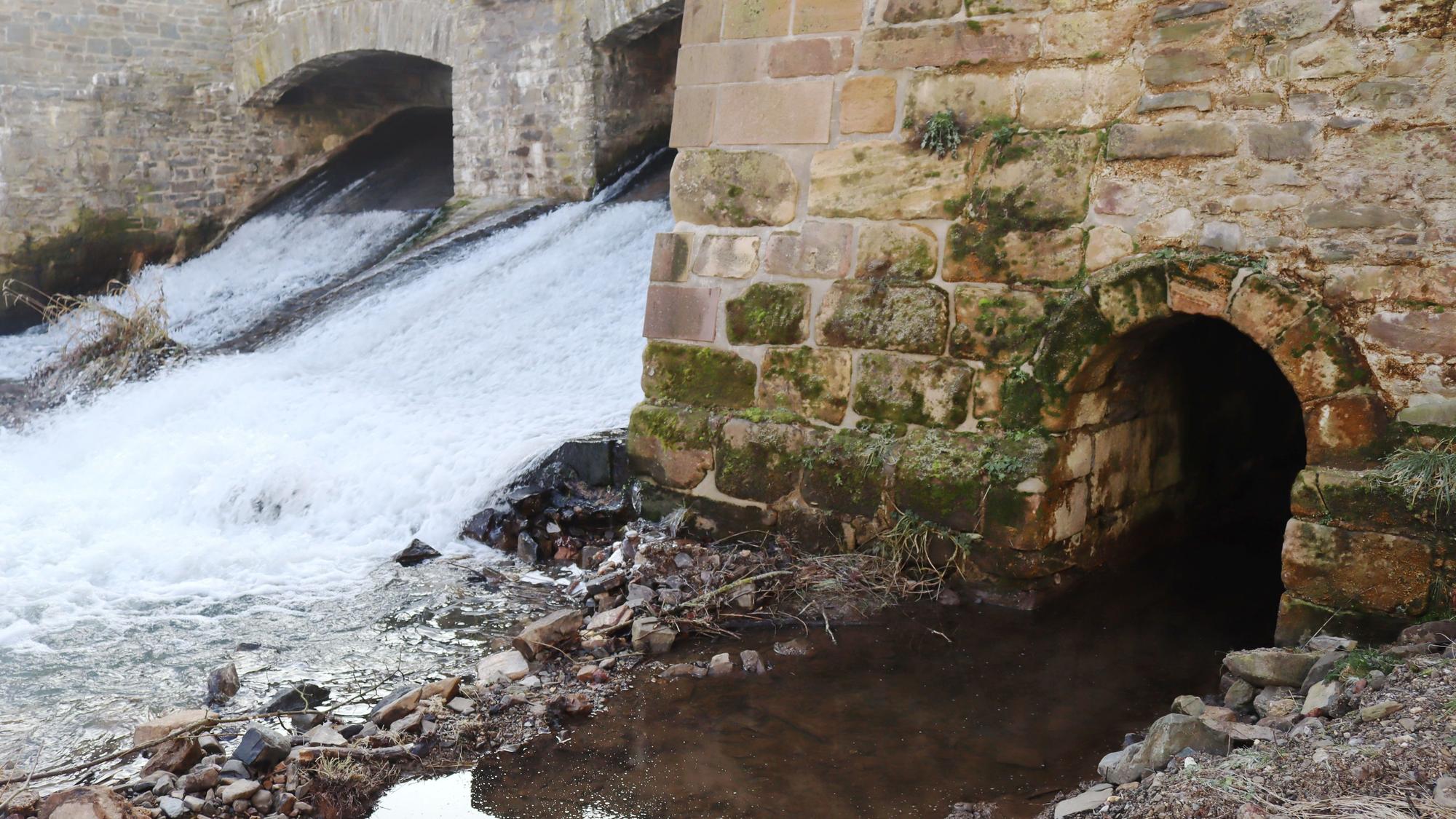 Ein Stolleneingang befindet sich unterhalb der Stadtmauer. Im Hintergrund fließt die Erft über die Wasserfälle in die Stadt.