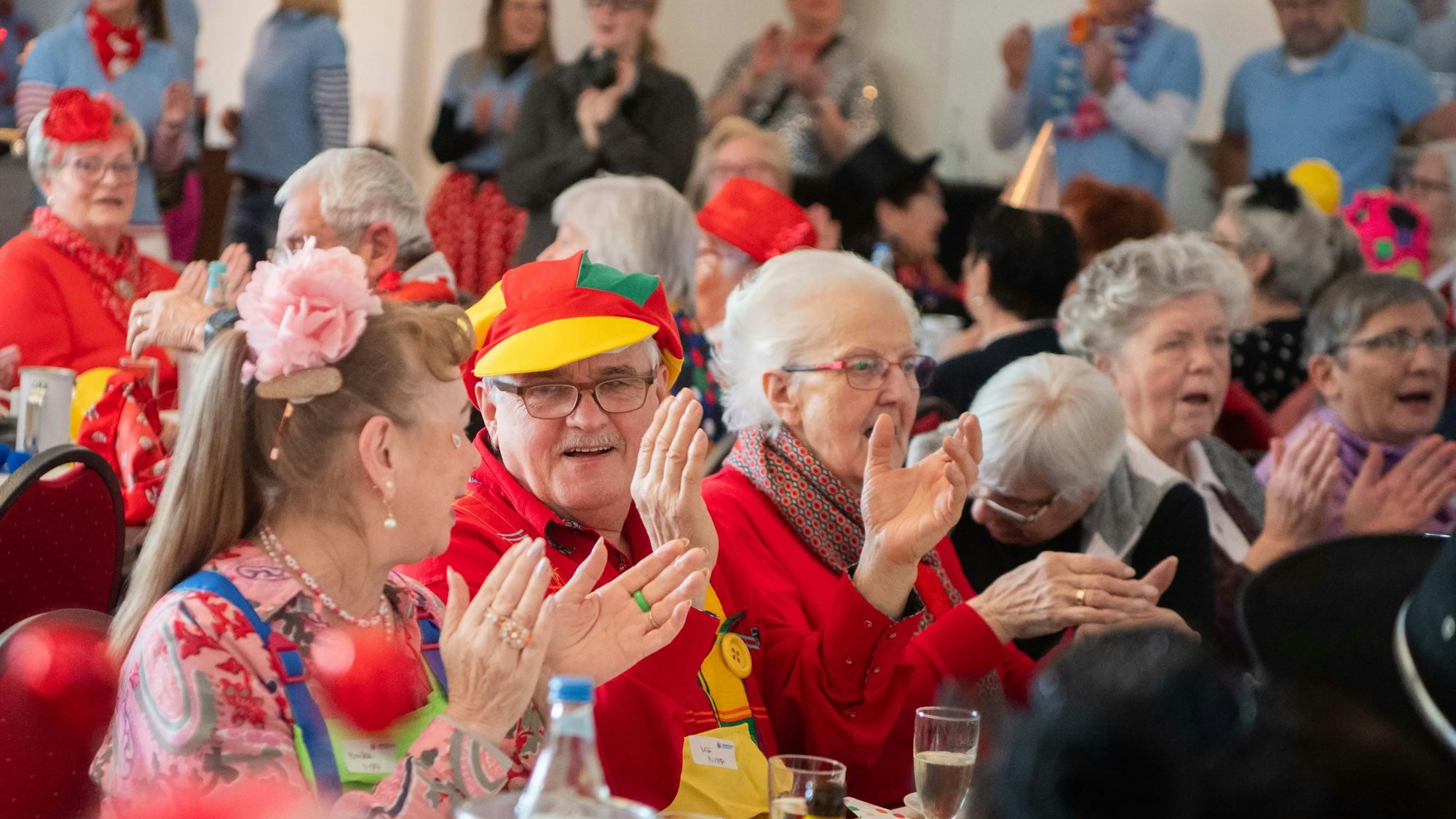 Viele Seniorinnen und Senioren feiern in einem Saal in Kreuzweingarten Karneval und klatschen zur Musik.