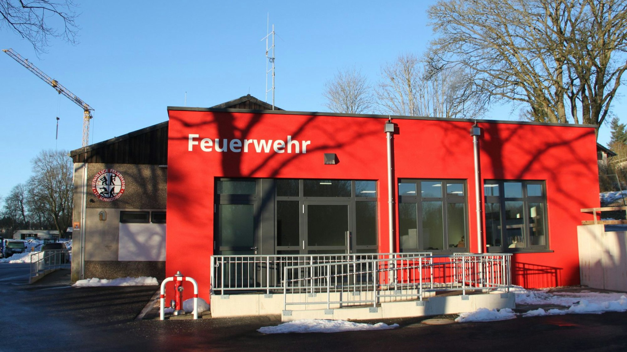 Vor dem bisherigen Gerätehaus der Feuerwehr in Dahlem-Schmidtheim ist der neue Anbau, der in der Signalfarbe Rot angestrichen ist.