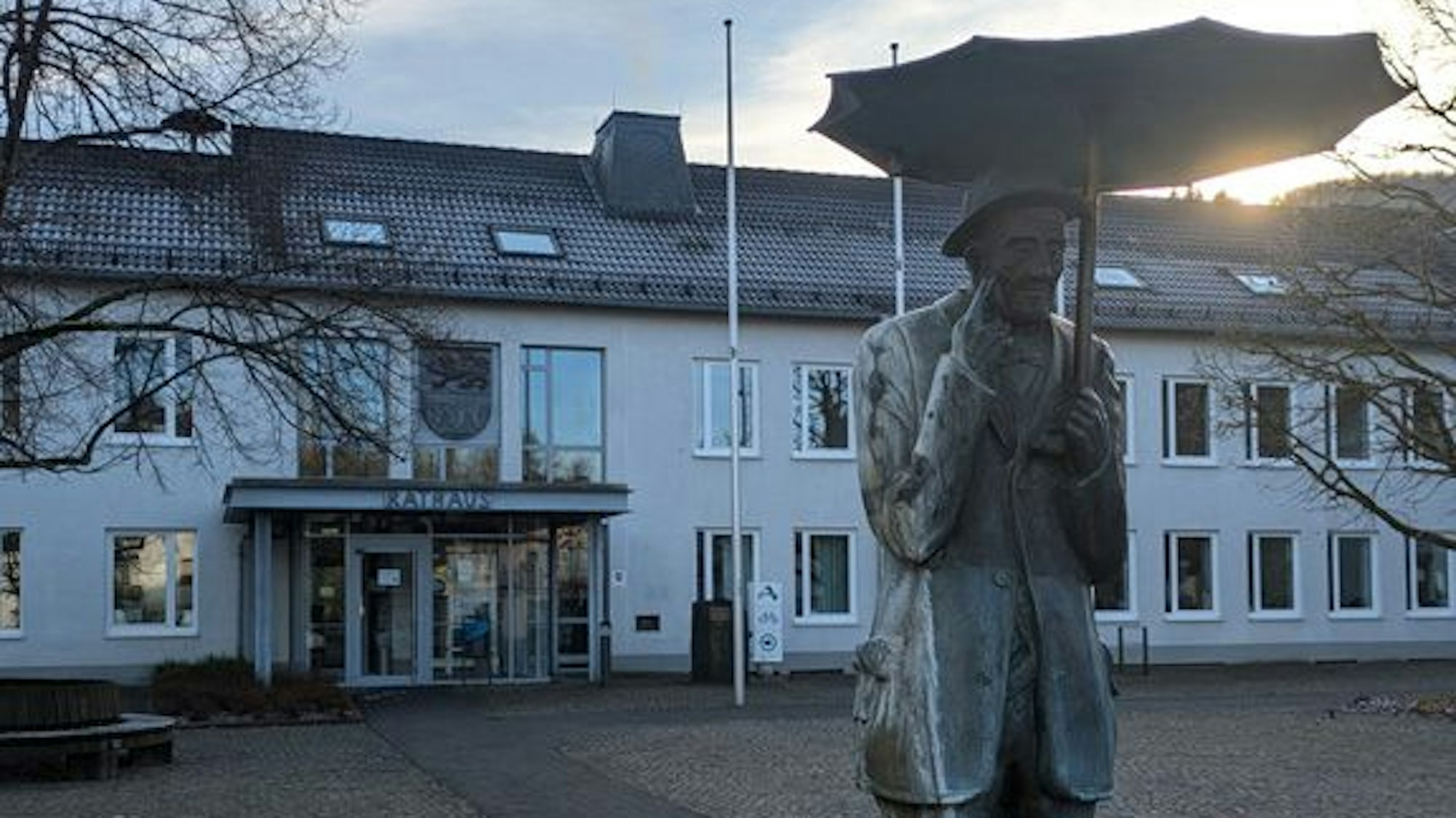 Die Gemeinde Morsbach hat ihr Rathaus neu organisiert. Davon völlig ungerührt ist das Morsbacher Original Rähn Willem. Unser Foto zeigt das Rathaus und davor die Skulptur des Ur-Morsbachers.