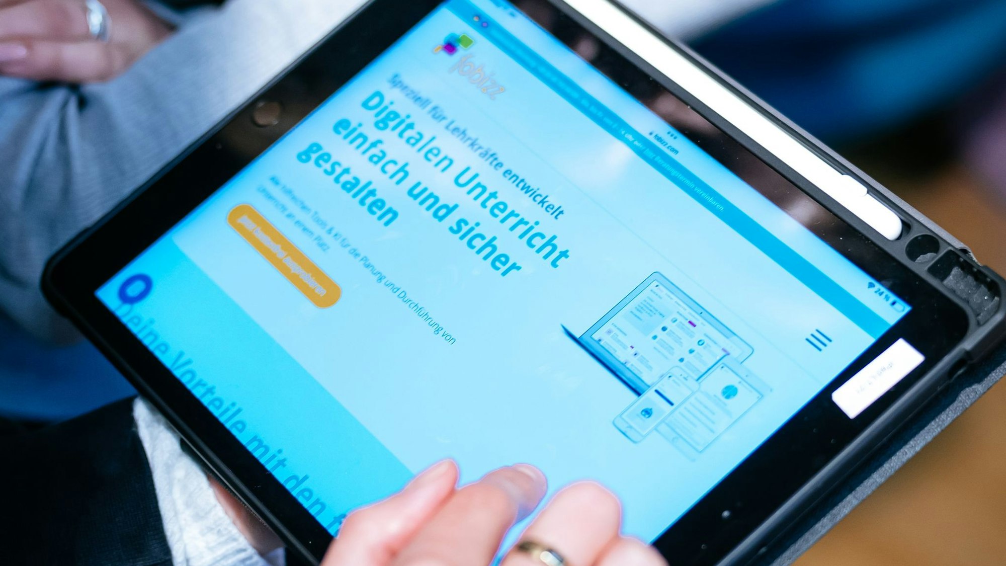 Eine Frau hält ein Tablett, auf dem die Startseite der Plattform „fobizz“ geöffnet ist.